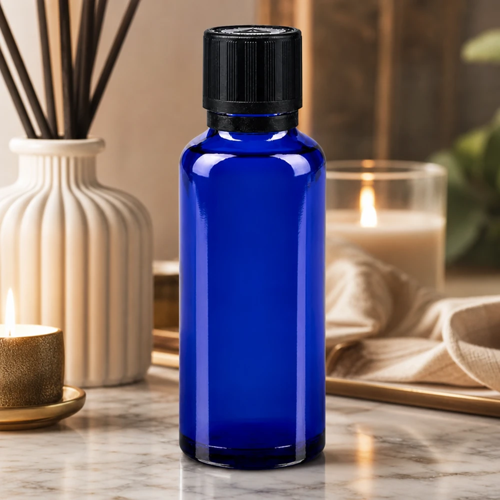 flacon à pharmacie bleu 30ml bouchon inviolable 1mm noir séc. enf. ada.a.ave. bouchon inviolabilité Flacon en verre bleu de 30 ml avec bouchon à vis noir à sécurité enfant, posé sur du marbre avec des bougies