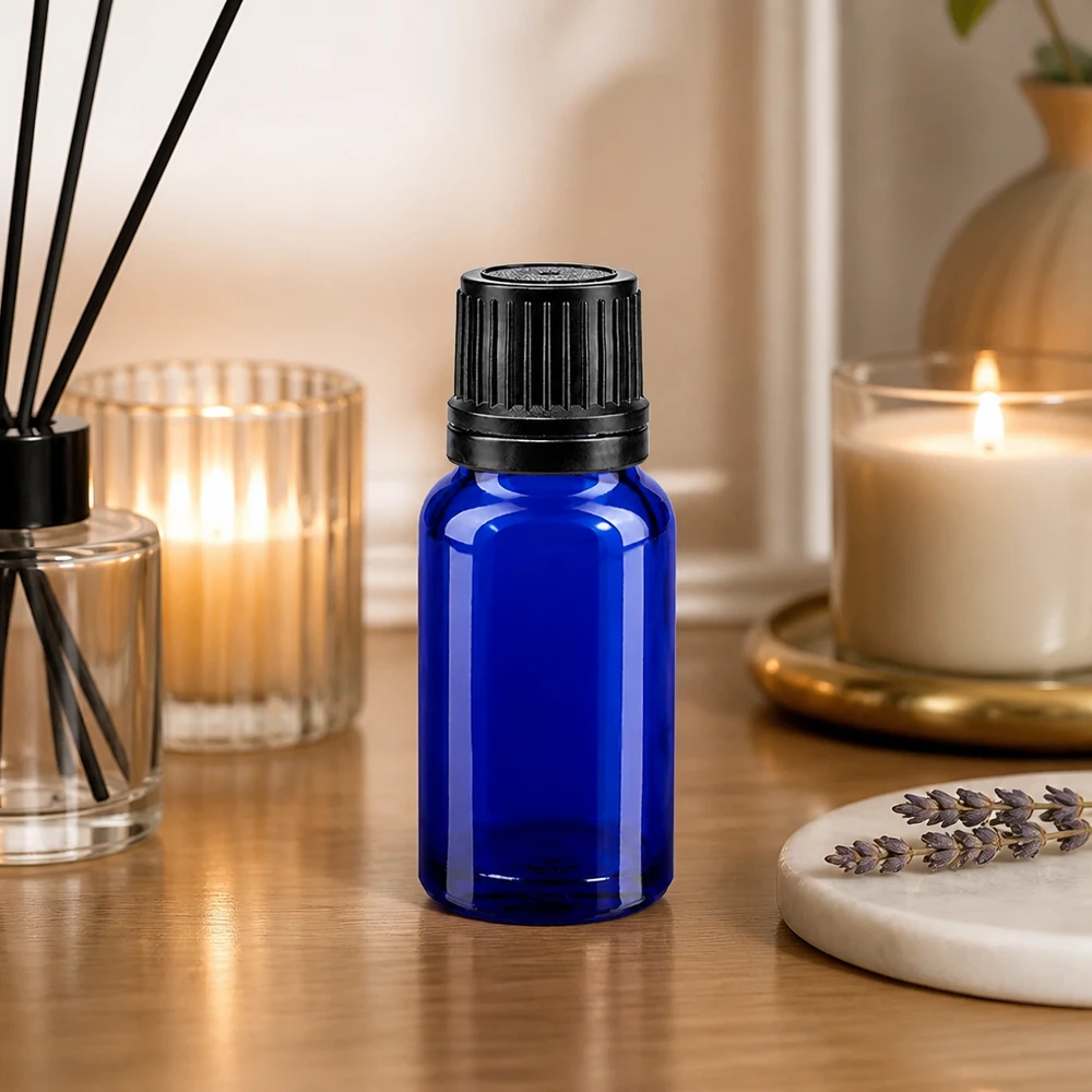 Flacon en verre bleu de 10 ml avec compte-gouttes de 1 mm et bouchon OV, à côté de la lavande et des bougies