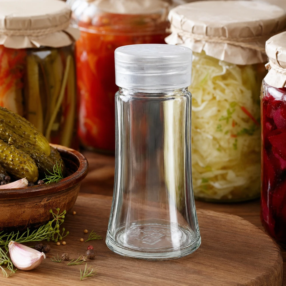 Pot à sel/épices 95 ml avec saupoudreuse, blanc Bocal à sel bombé de 95 ml avec couvercle saupoudreur blanc, posé parmi des bocaux colorés sur une planche en bois