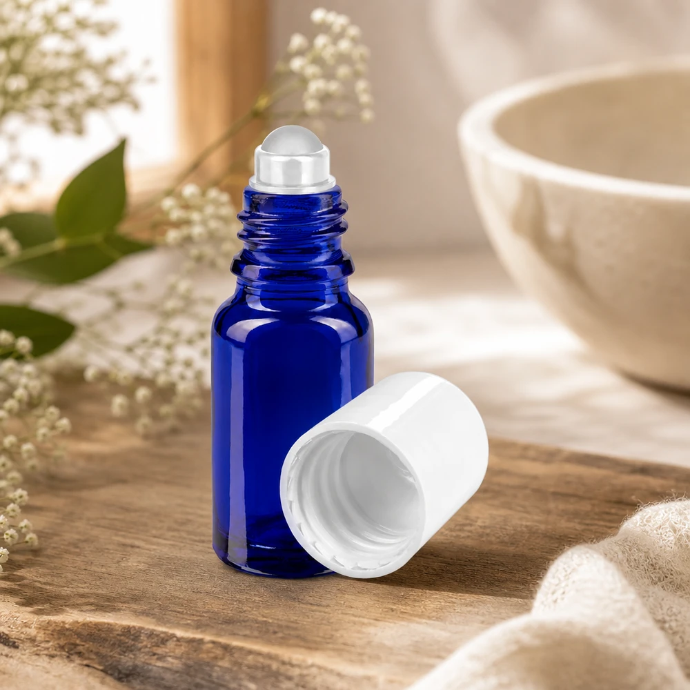 Flacon en verre d'apothicaire bleu de 10 ml muni d'un applicateur à bille et d'un bouchon blanc, contenant des fleurs séchées