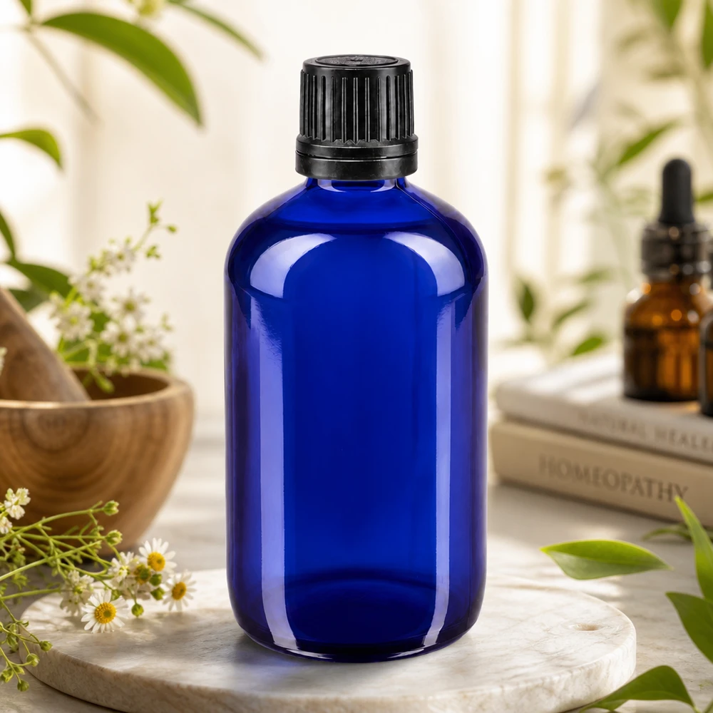 Bouteille de pharmacie bleue 100ml bouchon vissable bague de coulée noire bouchon inviolabilité Flacon en verre bleu cobalt de 100 ml avec bouchon à vis d'origine noir, présenté devant des ouvrages d'homéopathie