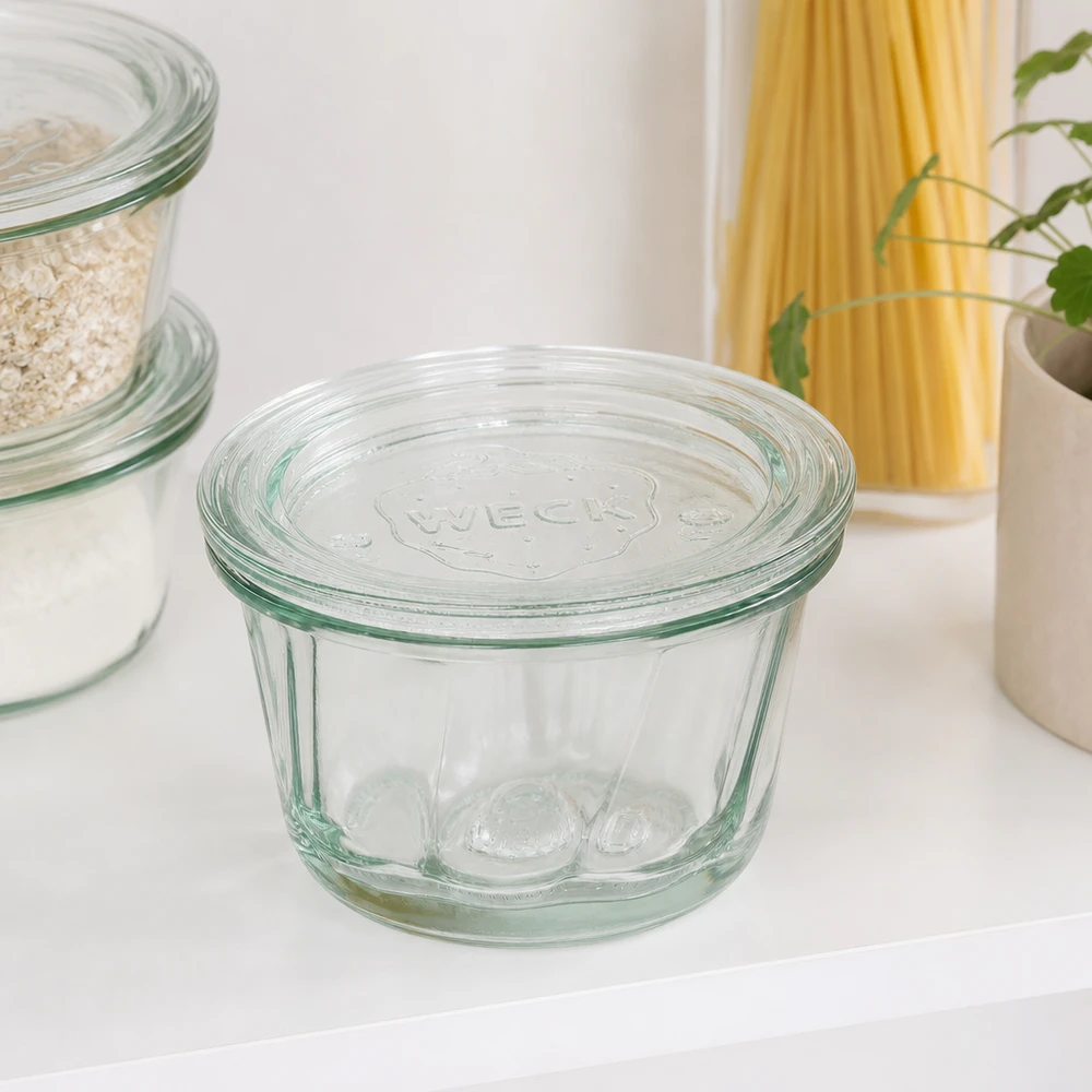 WECK Pot à kouglof RR80 165ml avec couvercle en verre sur le plan de travail blanc de la cuisine à côté des pâtes et des bocaux à provisions