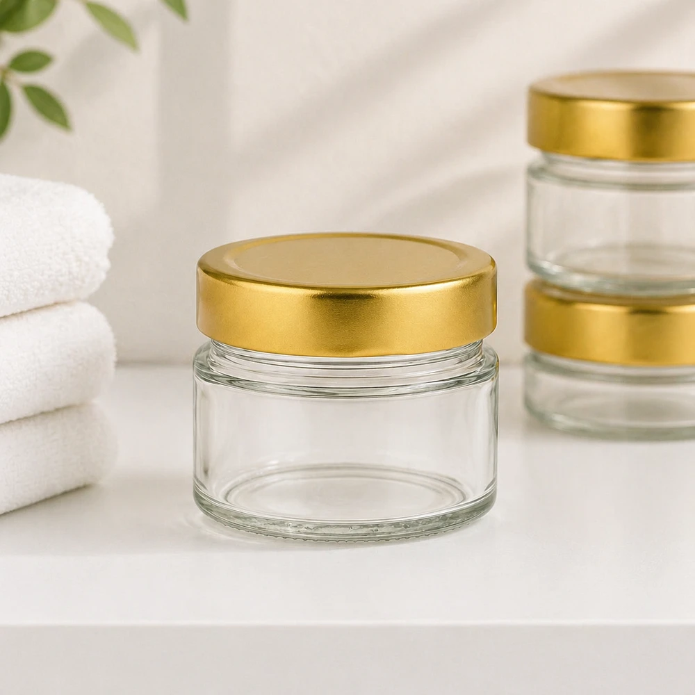 Pot rond de 80ml avec couvercle BasicSeal gold deep dans une ambiance salle de bain avec serviettes blanches pour cosmétiques