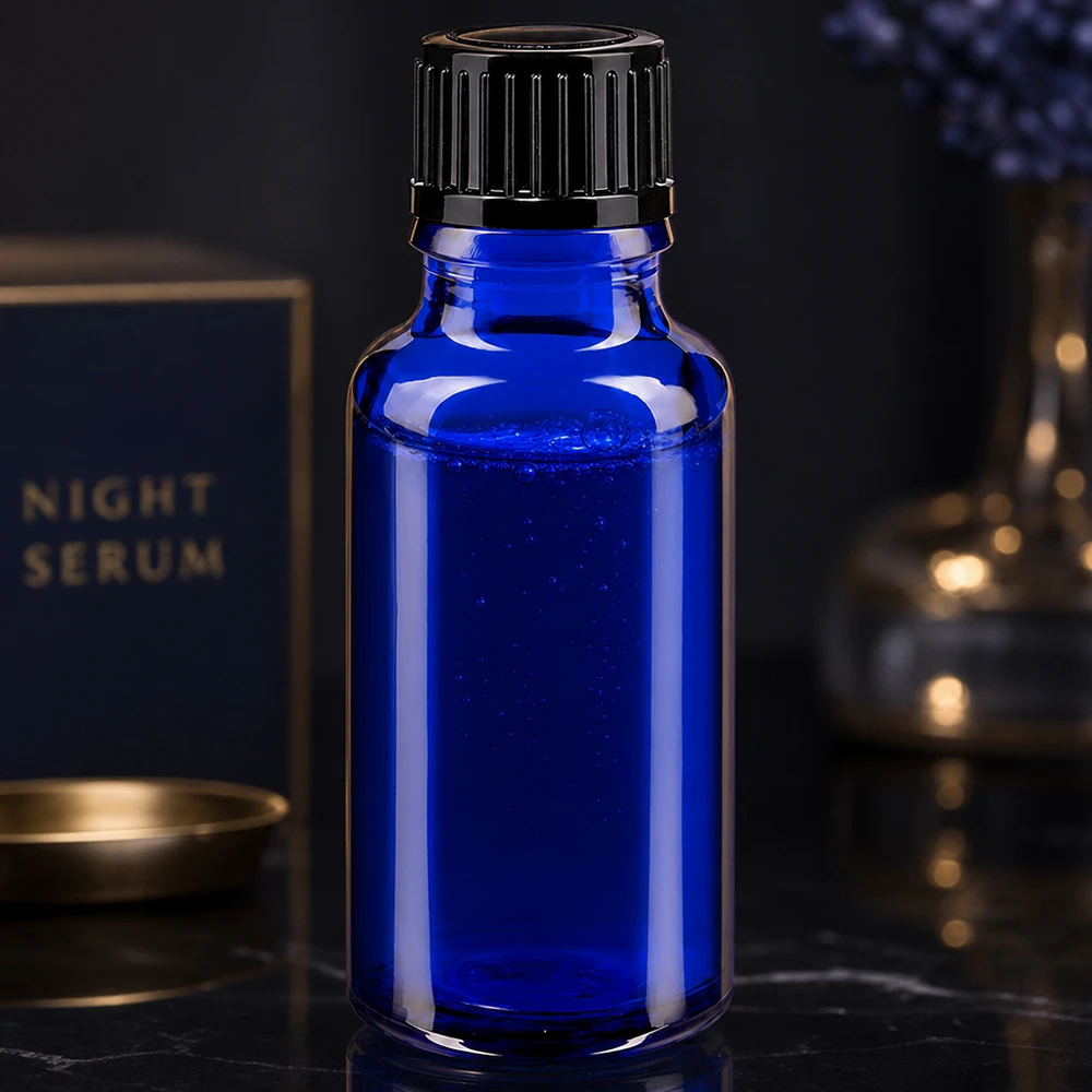 Flacon compte-gouttes STD de 20 ml bleu cobalt, contenant un sérum de nuit et muni d'un bouchon à vis noir