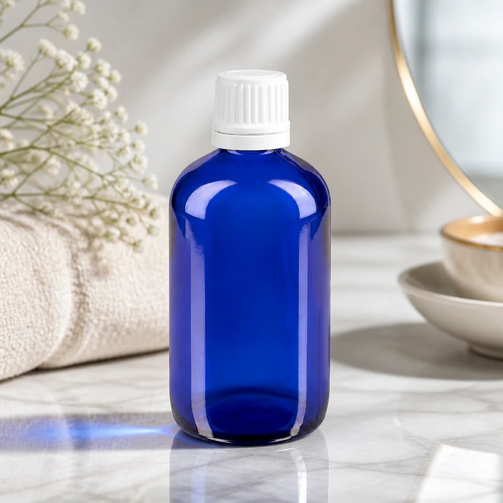 Flacon de pharmacie bleu cobalt de 100 ml avec bouchon blanc à sécurité enfant, dans un décor de salle de bains élégant