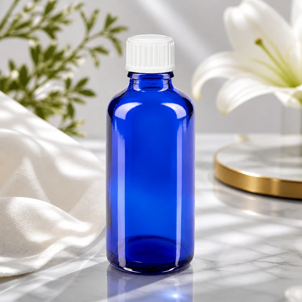 Flacon de pharmacie bleu cobalt de 50 ml, muni d'un bouchon blanc à sécurité enfants, devant un élégant arrangement floral
