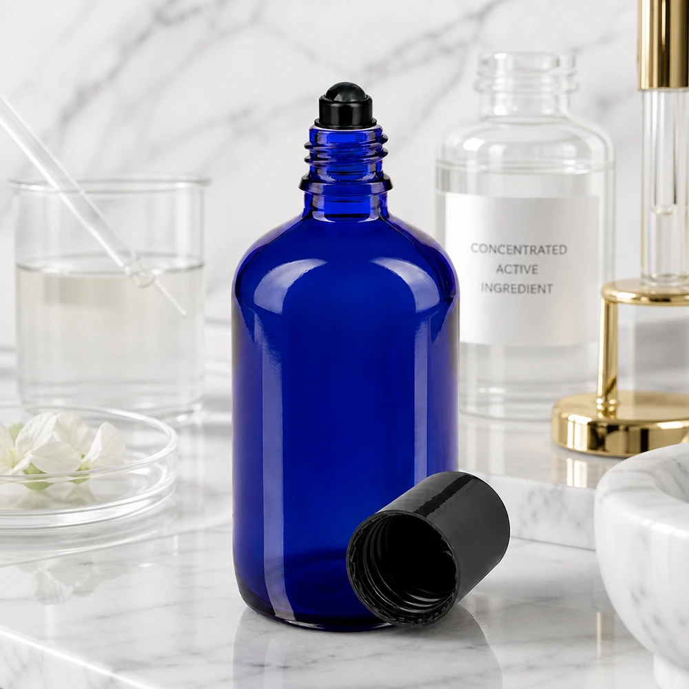 Flacon de déodorant en verre bleu 100 ml, déo à bille vide Un flacon en verre de pharmacie bleu de 100 ml muni d'un bouchon à bille, posé à côté d'un principe actif concentré sur du marbre