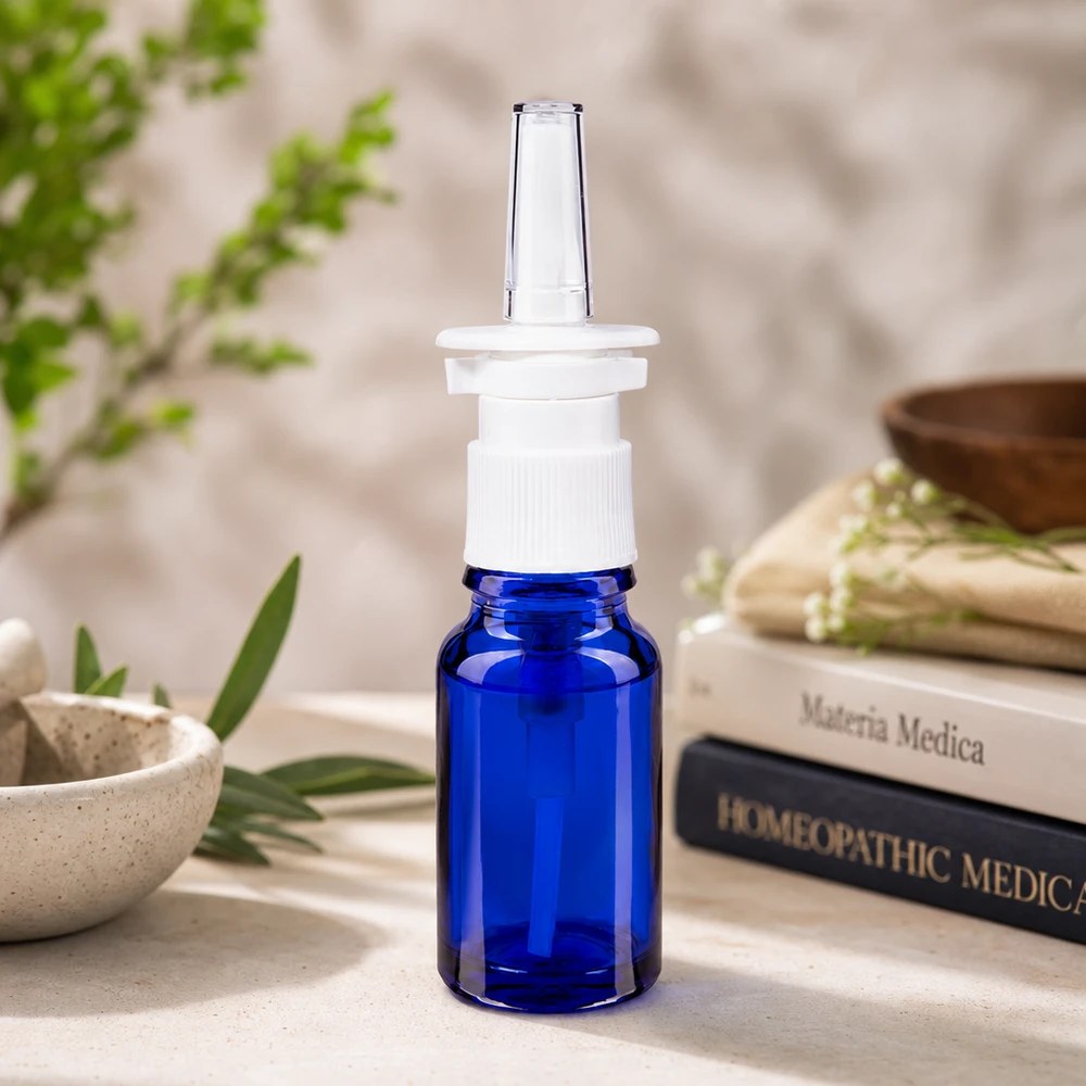 Flacon de pharmacie bleu de 10 ml avec embout pour spray nasal, présenté dans les ouvrages d'homéopathie « Materia Medica »