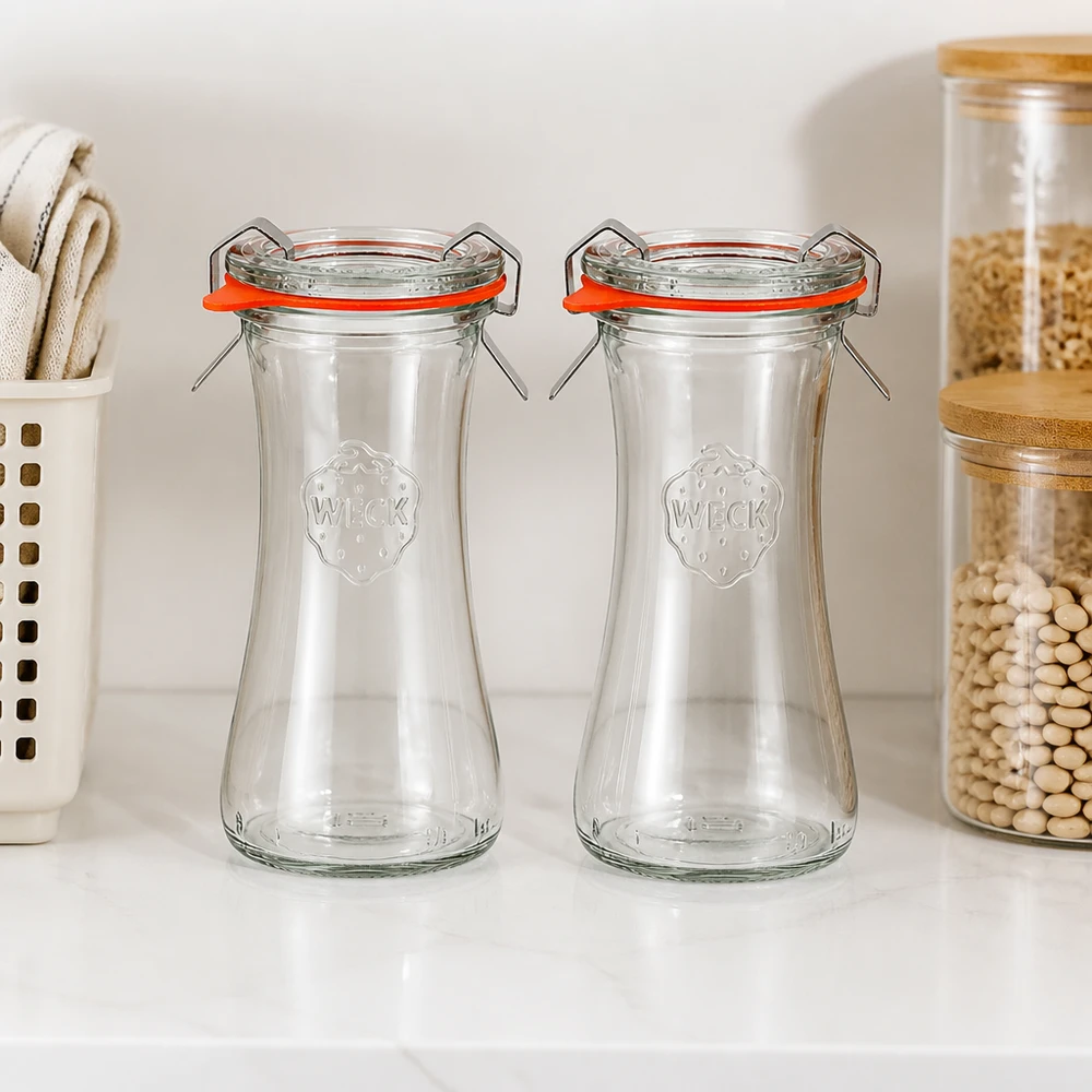 Deux pots à délicatesse vides WECK 100ml RR40 avec des anneaux en caoutchouc orange dans une cuisine moderne à côté des bocaux à provisions