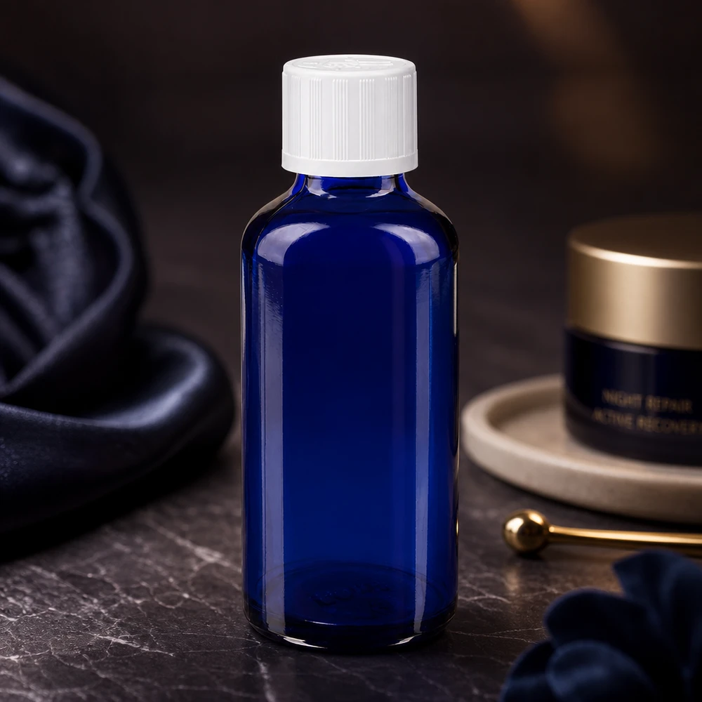 Flacon à pharmacie bleu 50ml bouchon vissable blanc séc. enf. std Flacon en verre d'apothicaire bleu de 50 ml avec bouchon à vis inviolable, à côté de produits de soin de nuit
