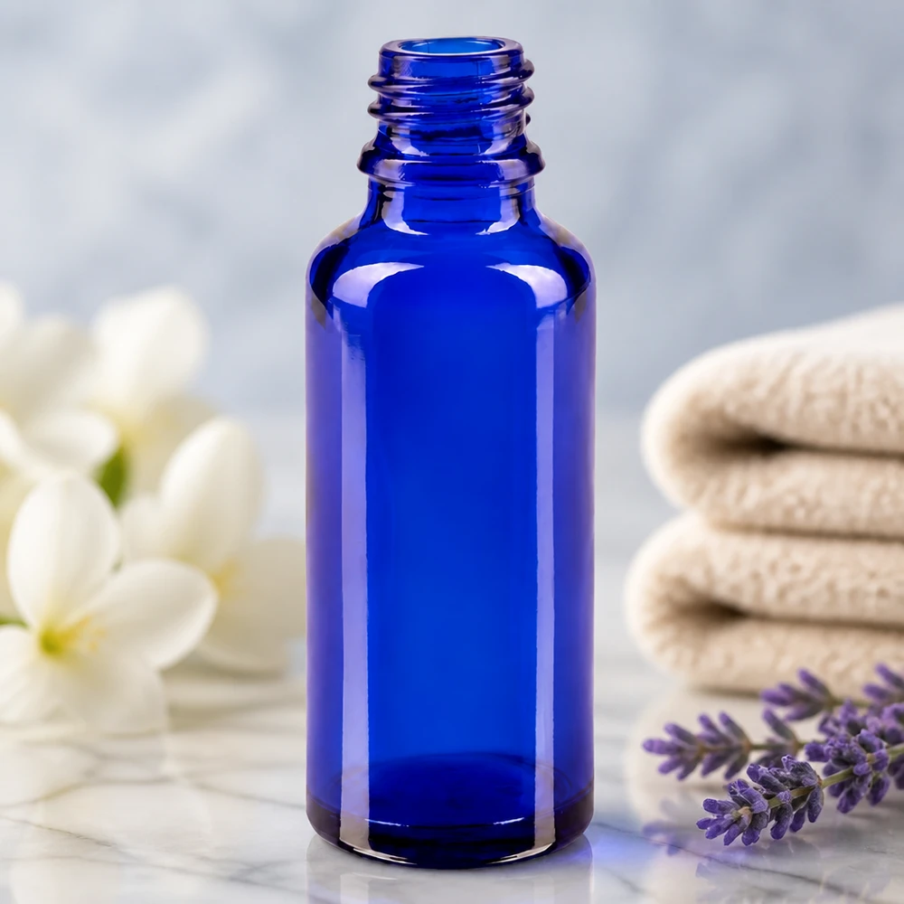 Flacon ApoGlas bleu cobalt de 30 ml posé sur du marbre, entouré de serviettes pliées, dans un décor de spa
