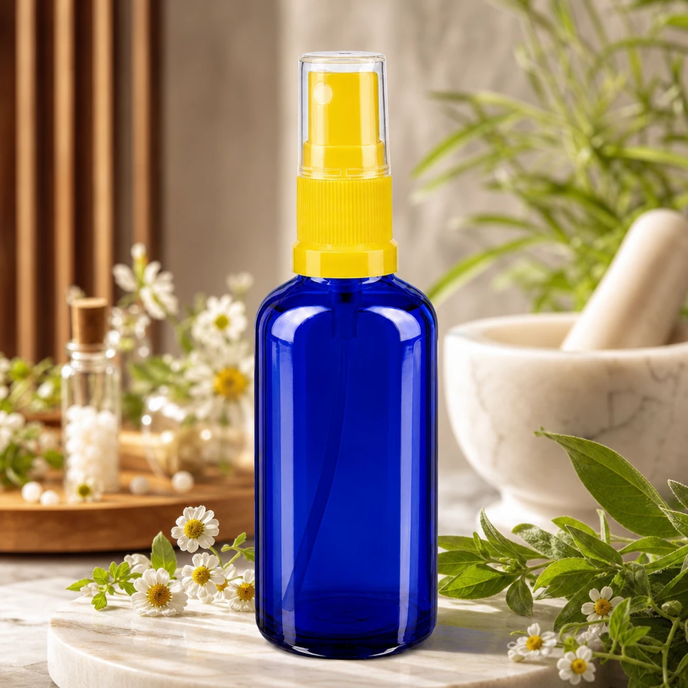 Flacon vaporisateur de 50 ml en Apoglas bleu avec une pompe jaune, à côté d'un mortier et d'herbes aromatiques