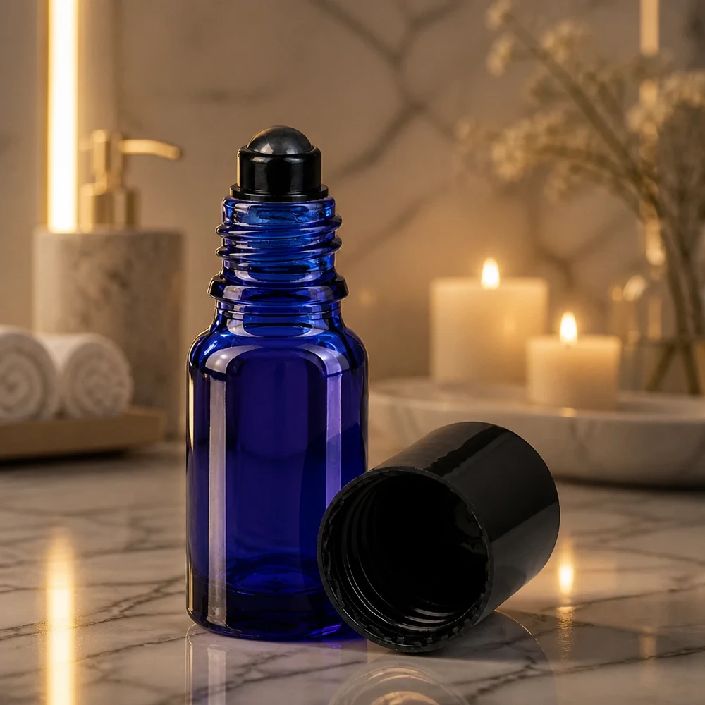 Flacon de déodorant en verre bleu 10 ml, déo à bille vide Petit flacon en verre d'apothicaire bleu de 10 ml muni d'un applicateur à bille, à côté de bougies allumées