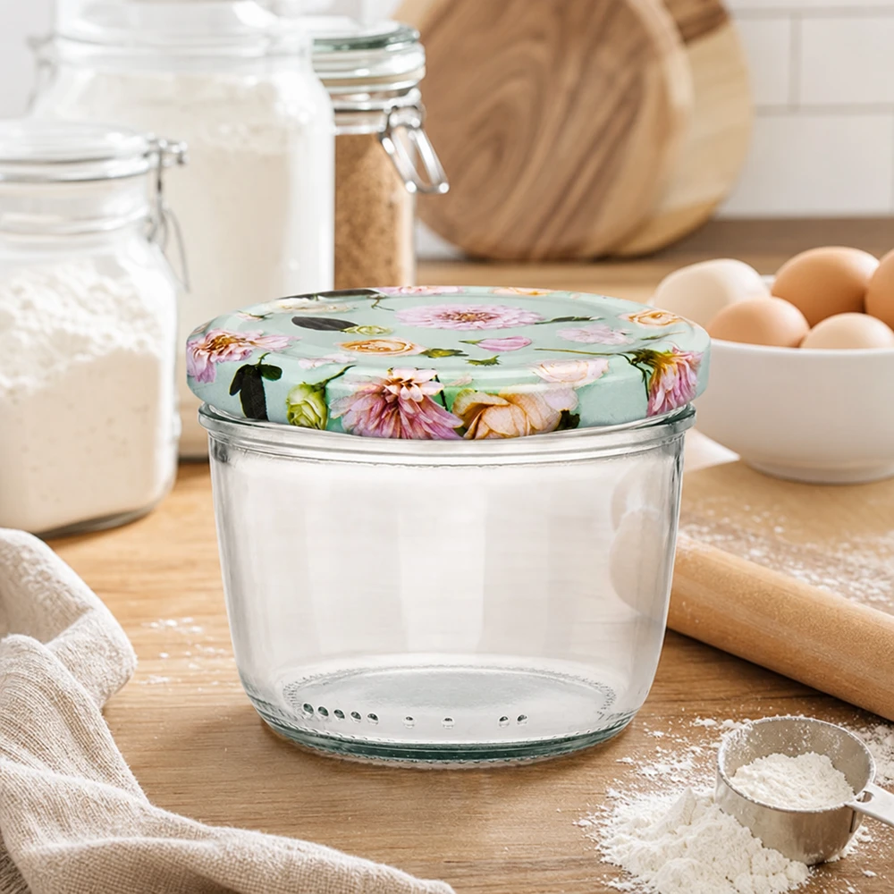 Verre renversé de 230 ml avec couvercle BasicSeal dans la cuisine lors de la cuisson, entouré de farine, d'œufs et d'ustensiles de cuisson