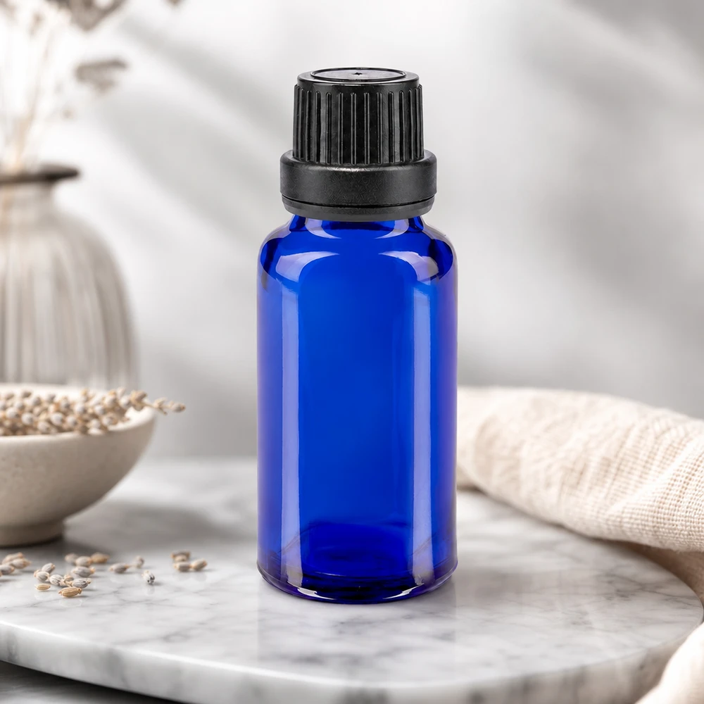 Flacon à pharmacie bleu 20ml bouchon à vis noir joint d'inviolabilité Petite bouteille en verre bleue de 20 ml avec bouchon à vis strié, posée sur un fond en marbre