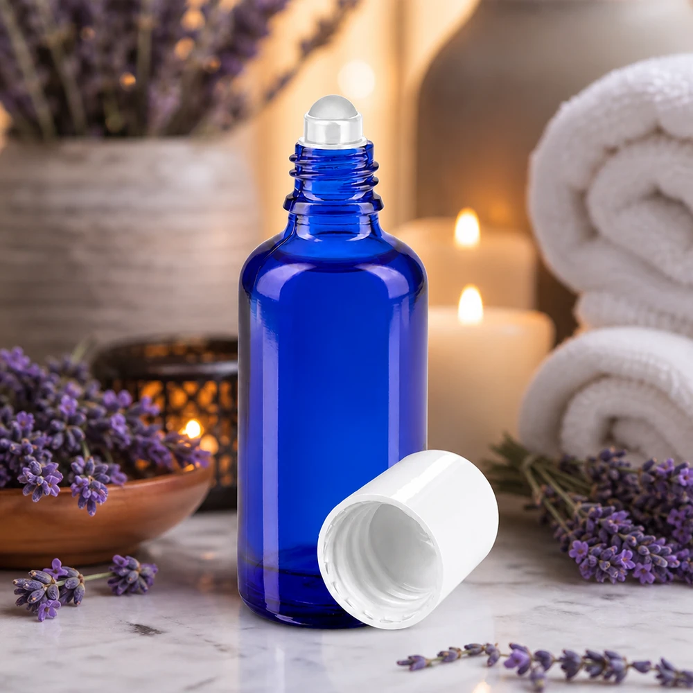 Rouleau en verre bleu de 50 ml, de qualité pharmaceutique, muni d'un applicateur à bille, devant un décor de lavande et des bougies
