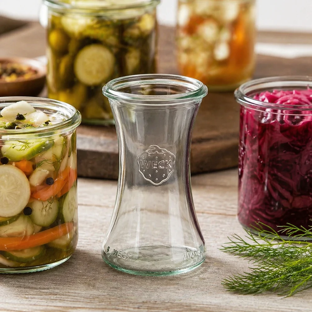 WECK RR60 Pot d'épicerie fine 200ml entre les bocaux de légumes colorés et les bocaux à conserves sur fond en bois