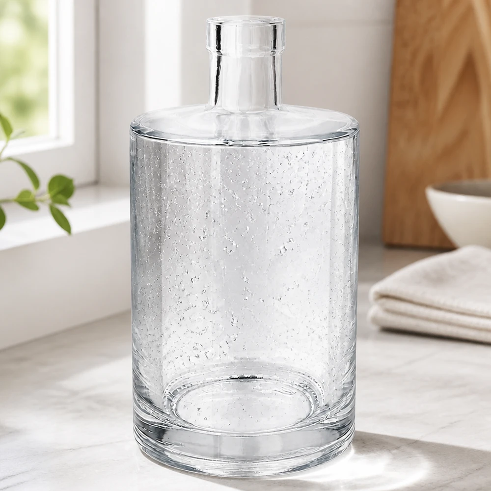 Bouteille en verre 700 ml « Marie » sans bouchon UNiTWIST® Elegante 700ml Glasflasche Marie mit Luftbläschen-Optik in modernem Wohnambiente neben Handtüchern und Holzschale