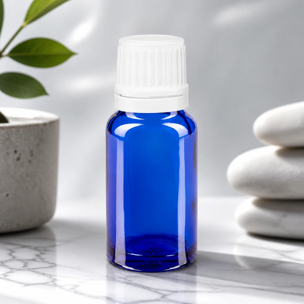 Flacon bleu cobalt de 10 ml avec embout compte-gouttes de précision de 0,7 mm, à côté de pierres Zen
