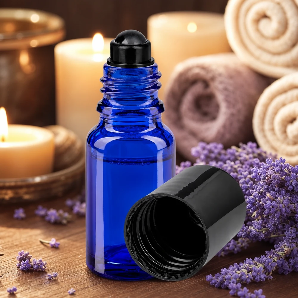 Flacon de déodorant en verre bleu 10 ml, déo à bille vide Flacon en verre à bille bleu cobalt de 10 ml, à côté de fleurs de lavande violettes et de bougies allumées