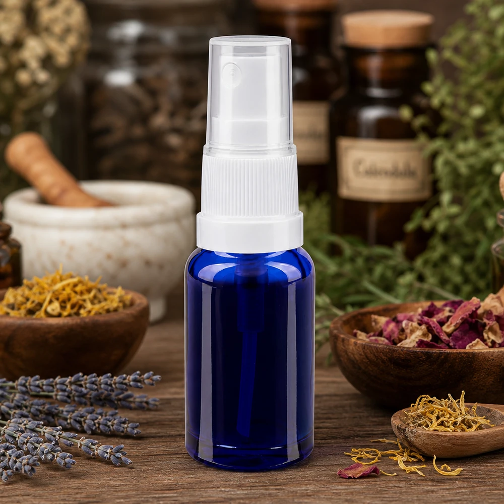 Petite bouteille en verre bleue munie d'un vaporisateur, à côté d'un mortier, avec des fleurs séchées et des flacons d'apothicaire en arrière-plan