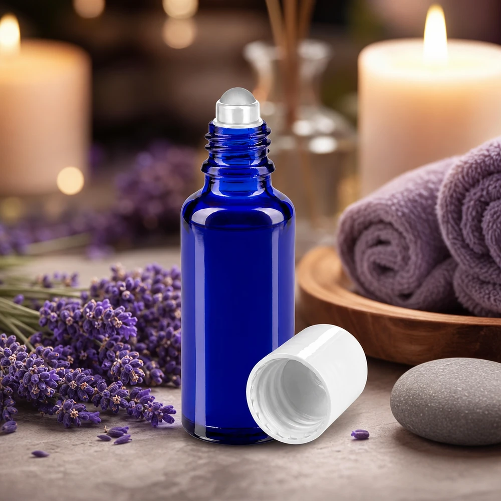 Flacon roll-on d'aromathérapie bleu de 30 ml avec bille en verre, devant des fleurs de lavande et des bougies