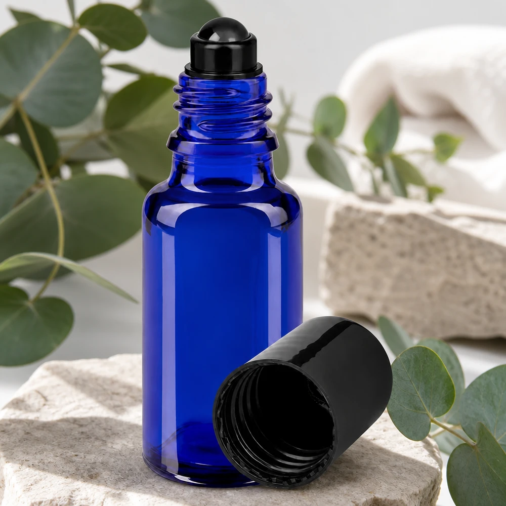 Flacon de déodorant en verre bleu 20 ml, déo à bille vide Flacon à bille bleu cobalt de 20 ml STD posé sur une pierre naturelle, orné de brindilles d'eucalyptus