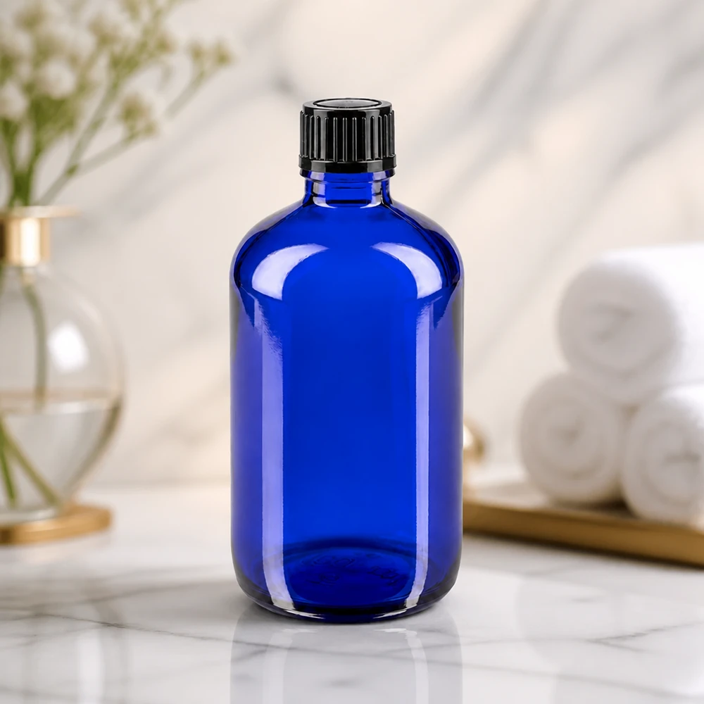 Flacon de pharmacie bleu 100ml bouchon vissable noir Std Flacon de pharmacie bleu cobalt de 100 ml posé à côté de serviettes blanches et d'un plateau doré dans une ambiance spa