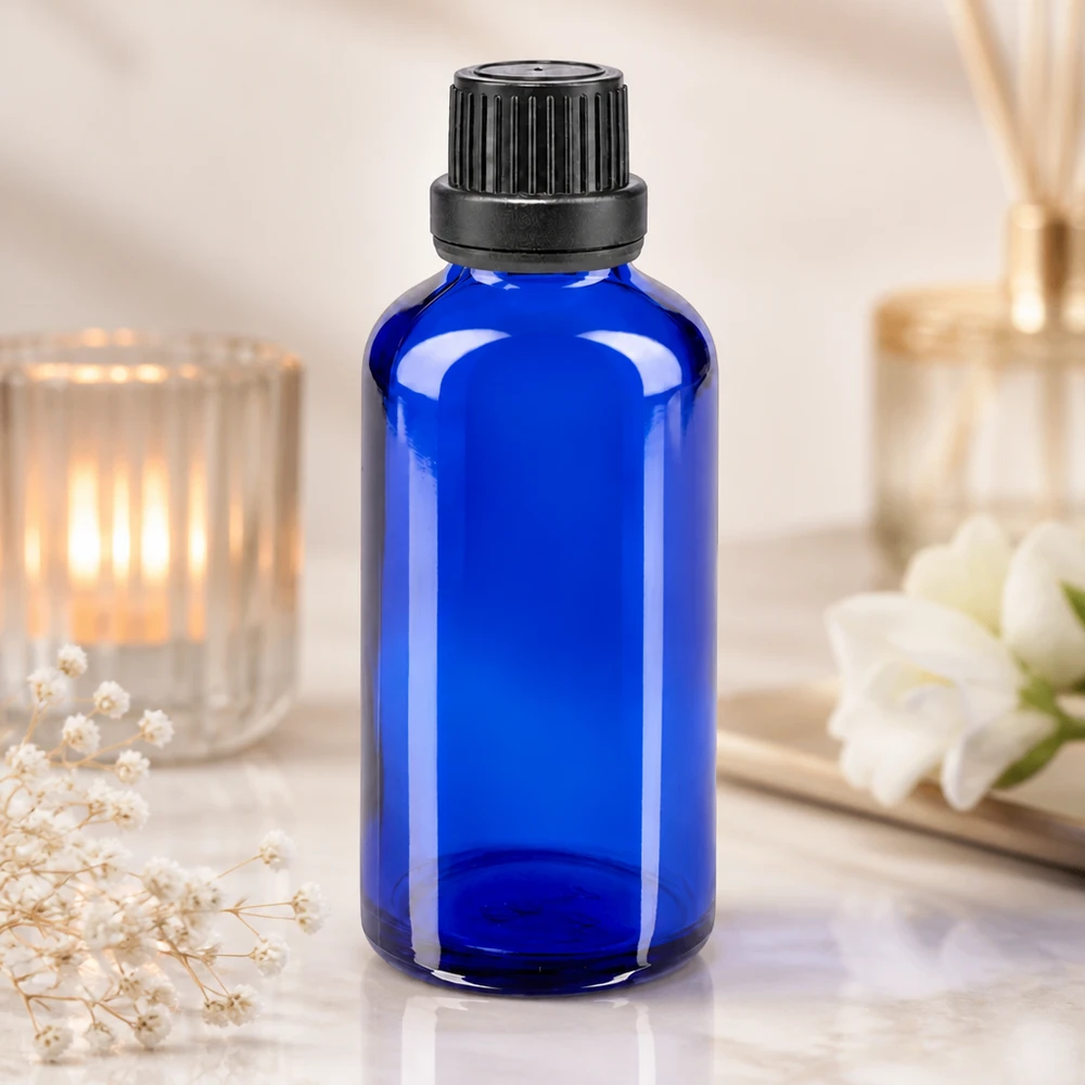 Flacon en verre d'apothicaire bleu de 50 ml muni d'un bouchon OV, posé sur une surface en marbre dans un cadre de bien-être raffiné