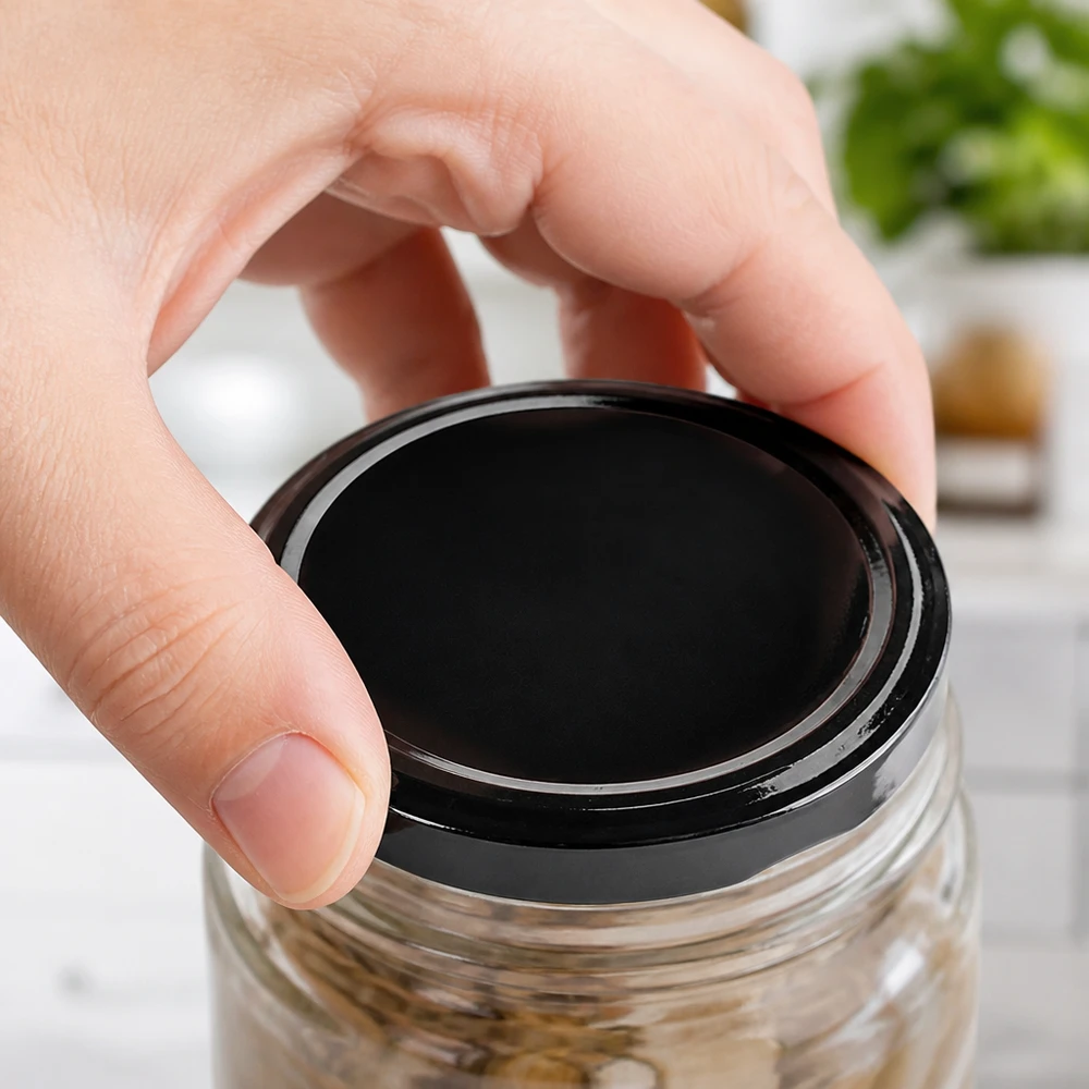 Bocal en verre contenant un produit foncé, équipé d'un couvercle noir BasicSeal TO63 de 63 mm de la marque UNiTWIST