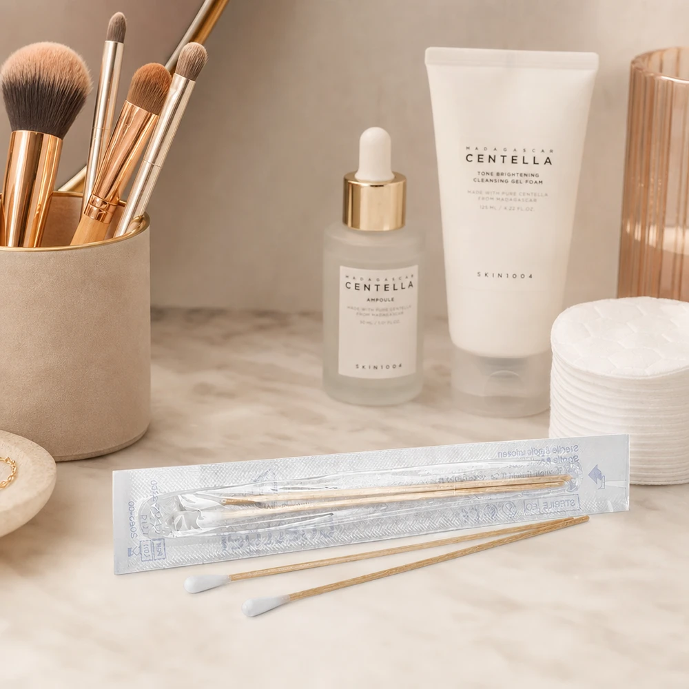 Des cotons-tiges emballés de manière hygiénique, avec une tête en coton blanc, présentés à côté de produits de soin de la peau et de maquillage