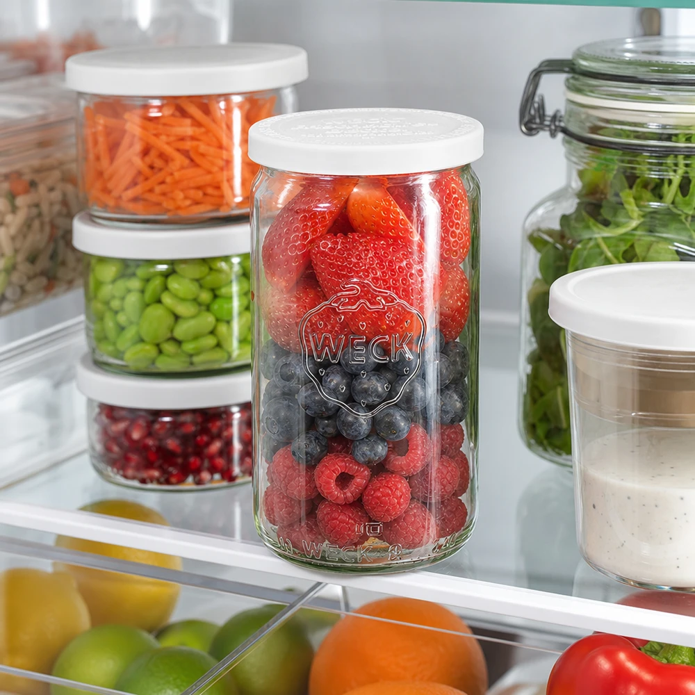 WECK Pot cylindrique 340ml rempli de baies mélangées dans le réfrigérateur à côté d'autres bocaux de stockage avec des légumes