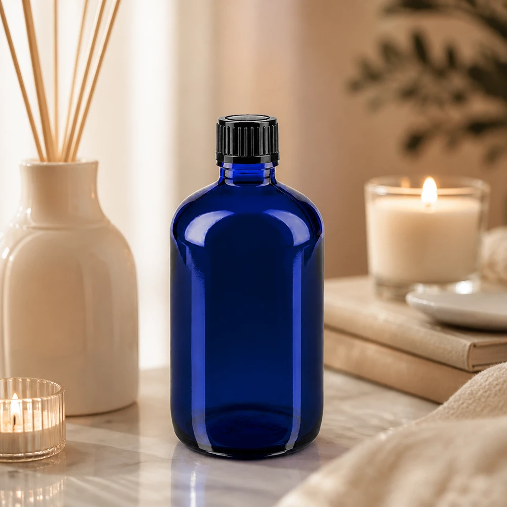 Flacon en verre bleu de 100 ml avec bouchon noir de 11 mm, dans une ambiance spa détendue