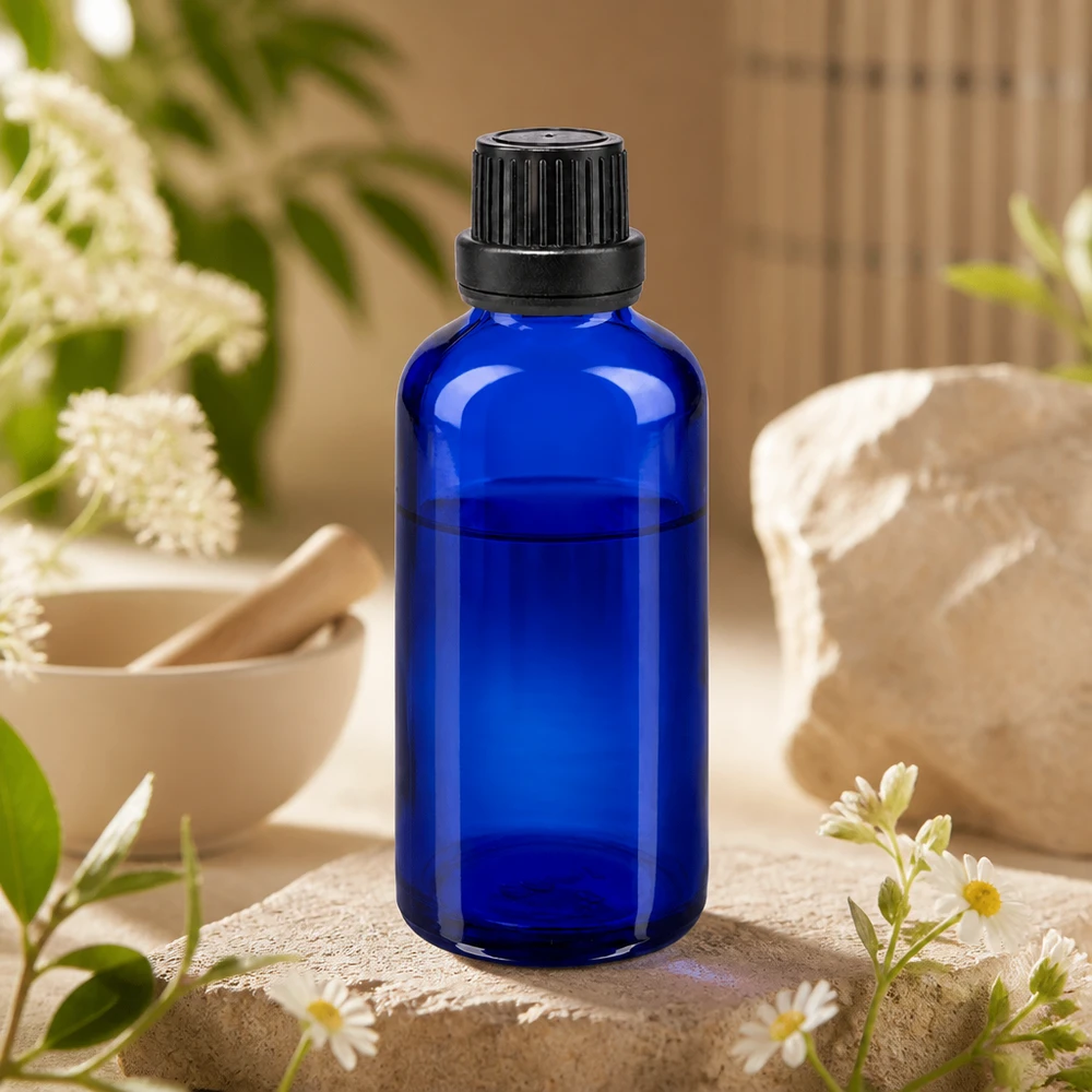 Flacon en verre d'apothicaire bleu de 50 ml, muni d'un bouchon OV et d'un compte-gouttes, entouré de fleurs sauvages blanches