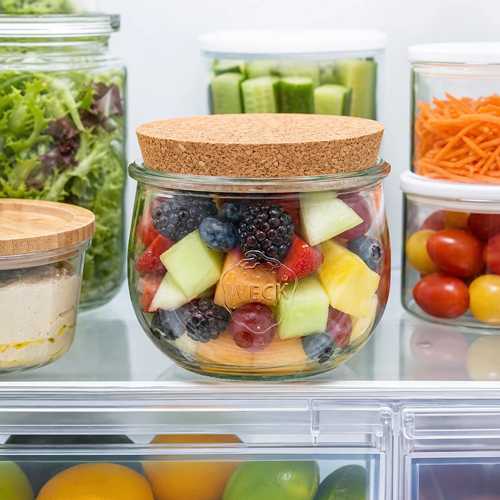 WECK Pot tulipe 580ml avec couvercle en liège dans le réfrigérateur rempli de salade de fruits à côté d'autres bocaux de stockage avec des légumes