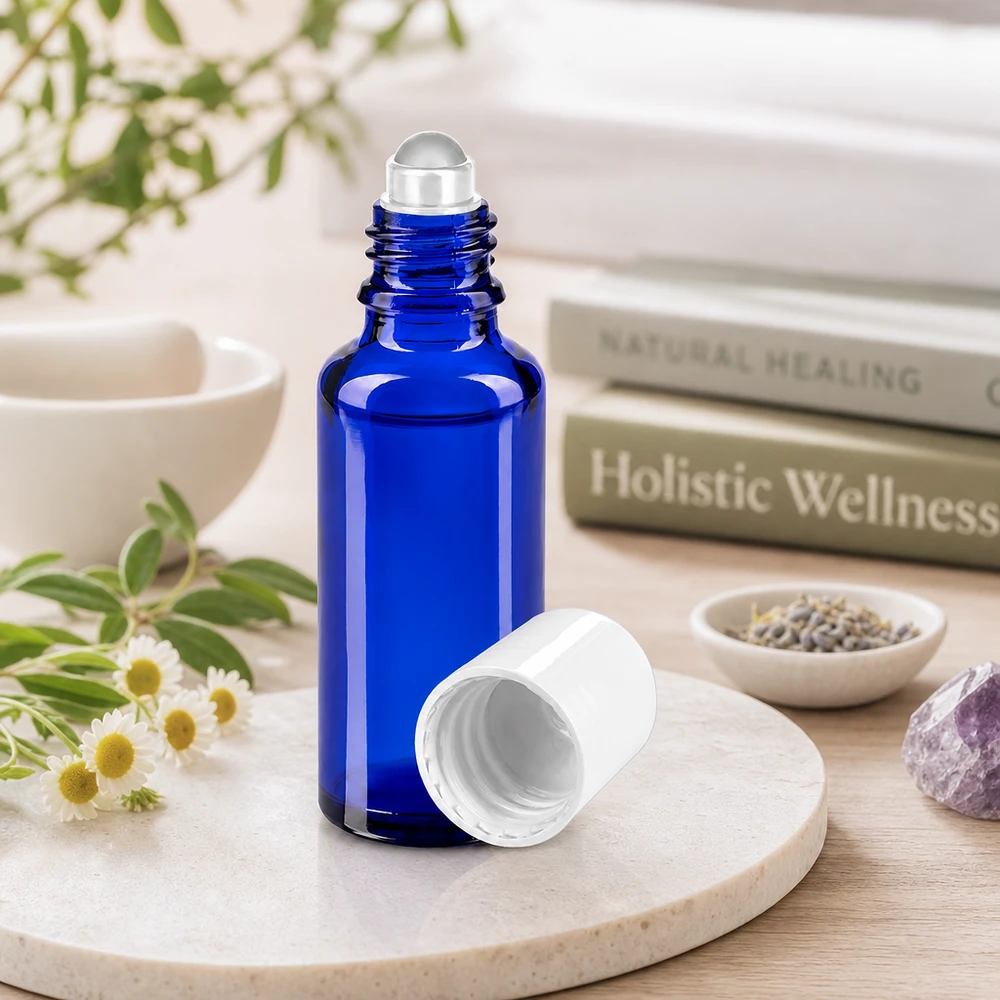 Flacon roulant en verre d'apothicaire bleu de 30 ml, ouvert sur un plateau en marbre, avec de la lavande et des pierres naturelles
