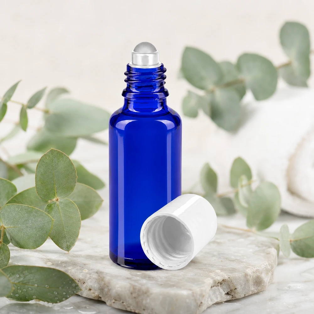 Flacon en verre bleu de 30 ml avec applicateur à bille pour huiles essentielles, sur un socle en pierre naturelle