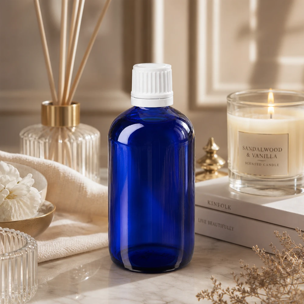 Flacon de pharmacie bleu 100ml bouchon vissable blanc bouchon inviolabilité Flacon en verre bleu cobalt de 100 ml avec bouchon OV blanc, dans une ambiance spa élégante avec parfum d'ambiance