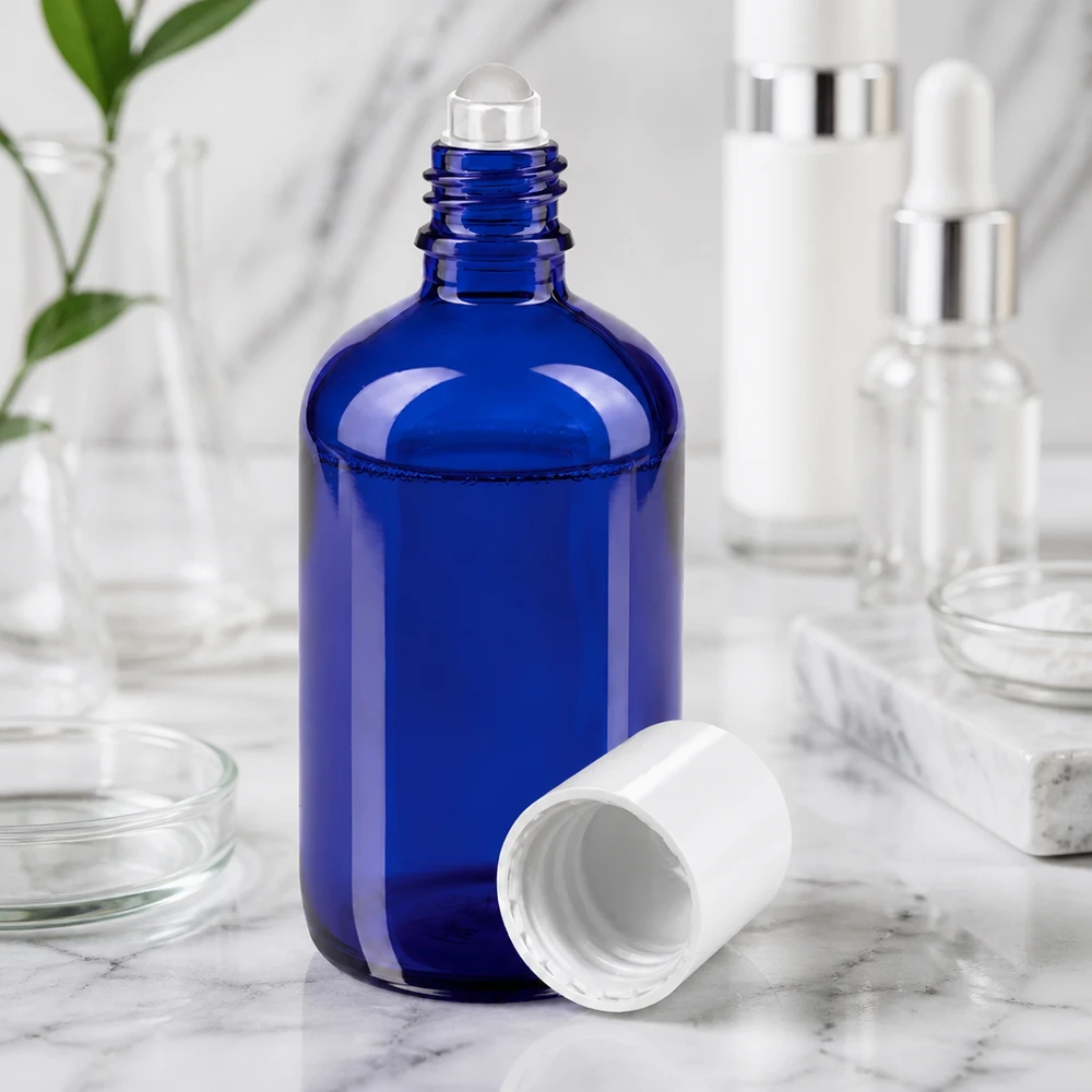 Flacon roll-on bleu cobalt de 100 ml avec une bille transparente et un bouchon blanc ouvert