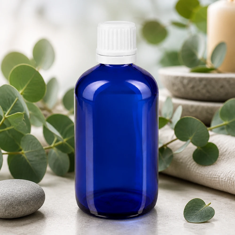 Flacon de pharmacie bleu 100ml bouchon compte-gouttes 1.2mm blanc bouchon inviolabilité Flacon compte-gouttes ApoGlas de 100 ml, bleu cobalt avec étiquette blanche, sur fond naturel d'eucalyptus