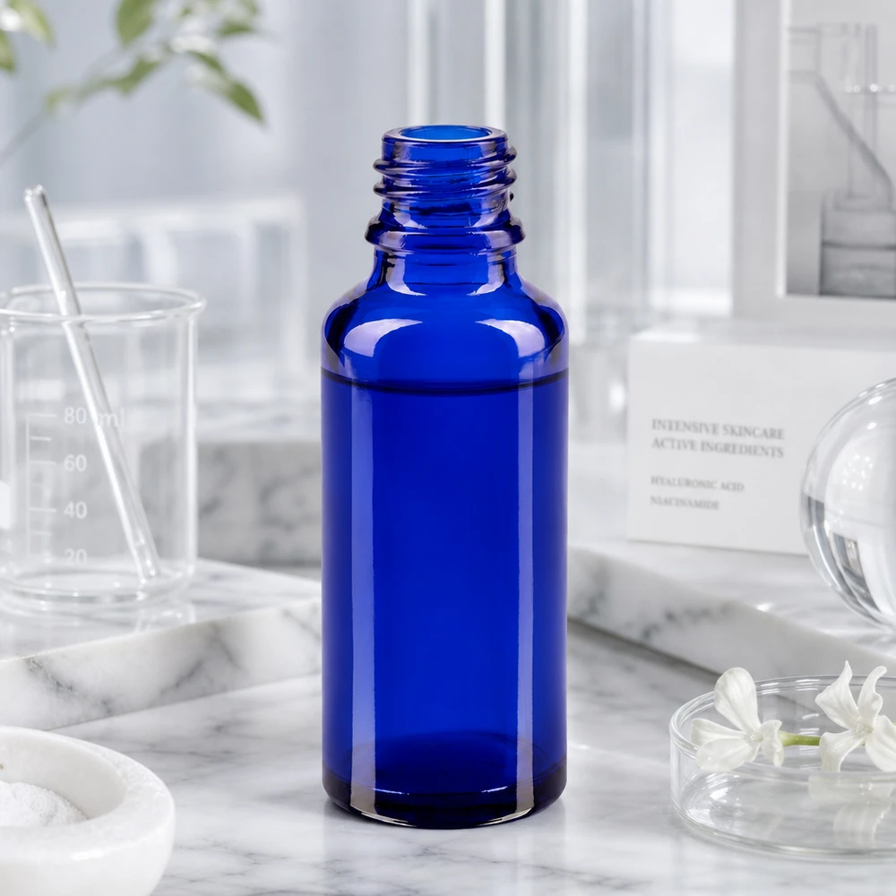 Flacon de pharmacie bleu vide ApoGlas de 30 ml avec bouchon à vis ouvert, posé sur du marbre blanc