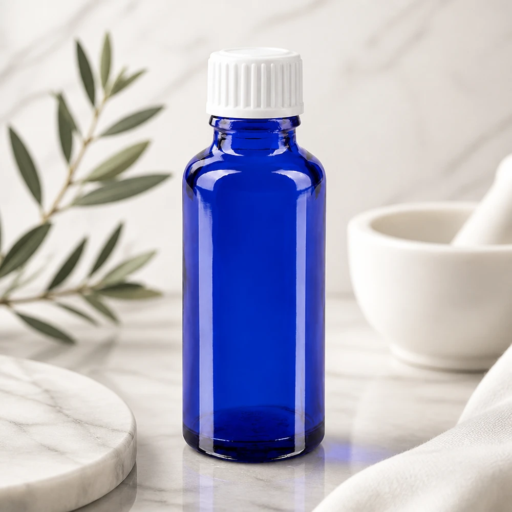 Flacon en verre bleu de 30 ml, modèle GR STD, muni d'un compte-gouttes de 3 mm, posé sur du marbre à côté d'un mortier et d'un pilon