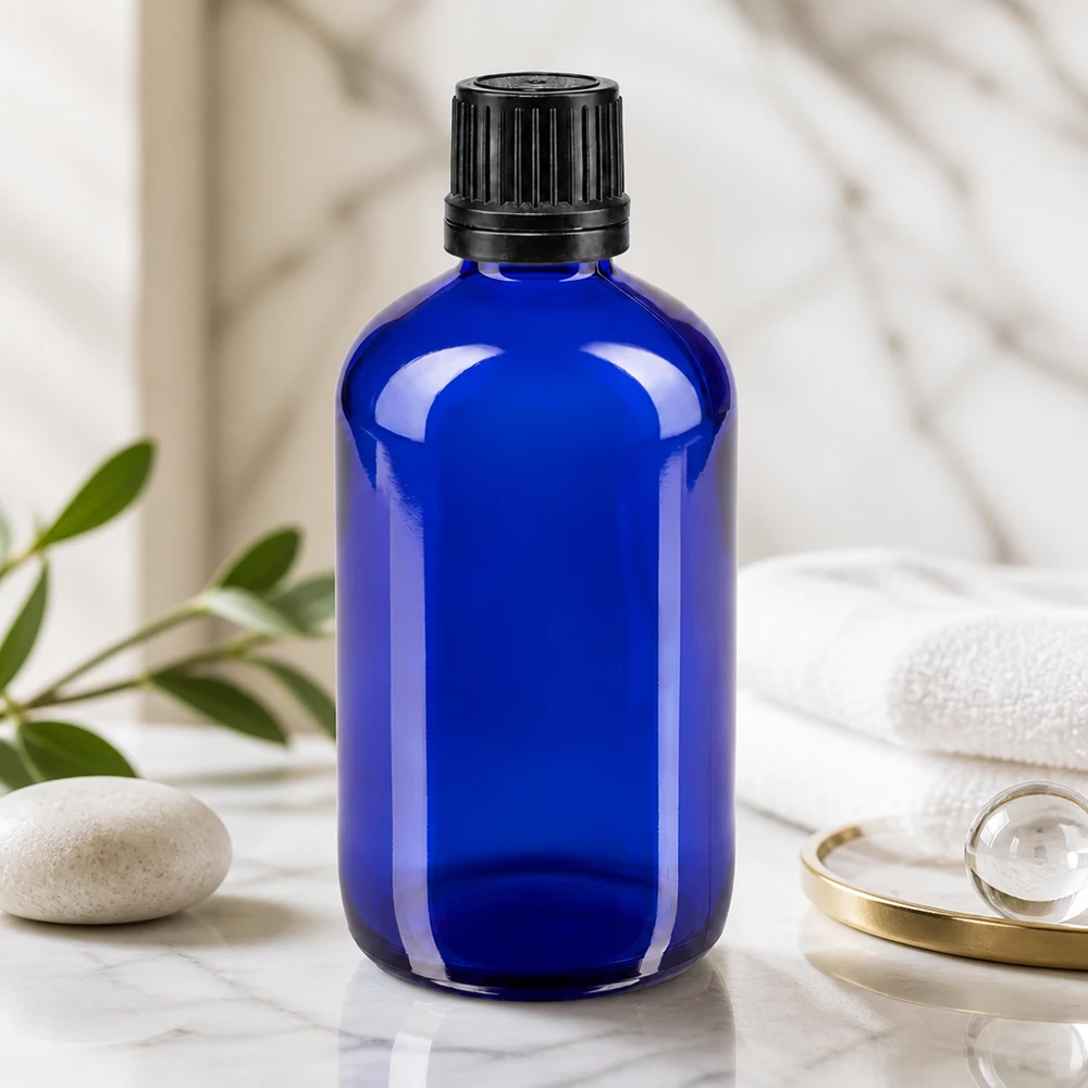 Bouteille de pharmacie bleue 100ml bouchon vissable bague de coulée noire bouchon inviolabilité Flacon en verre bleu de 100 ml muni d'un bouchon OV noir, posé sur du marbre à côté d'une serviette blanche