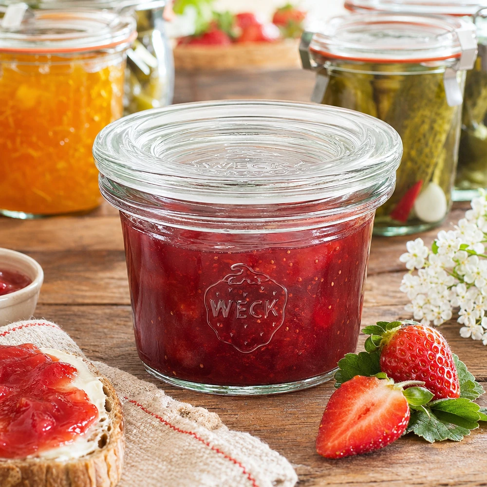 WECK Pot renversé 35ml RR40 rempli de confiture de fraises rouges à côté de fraises fraîches et de pain à la confiture