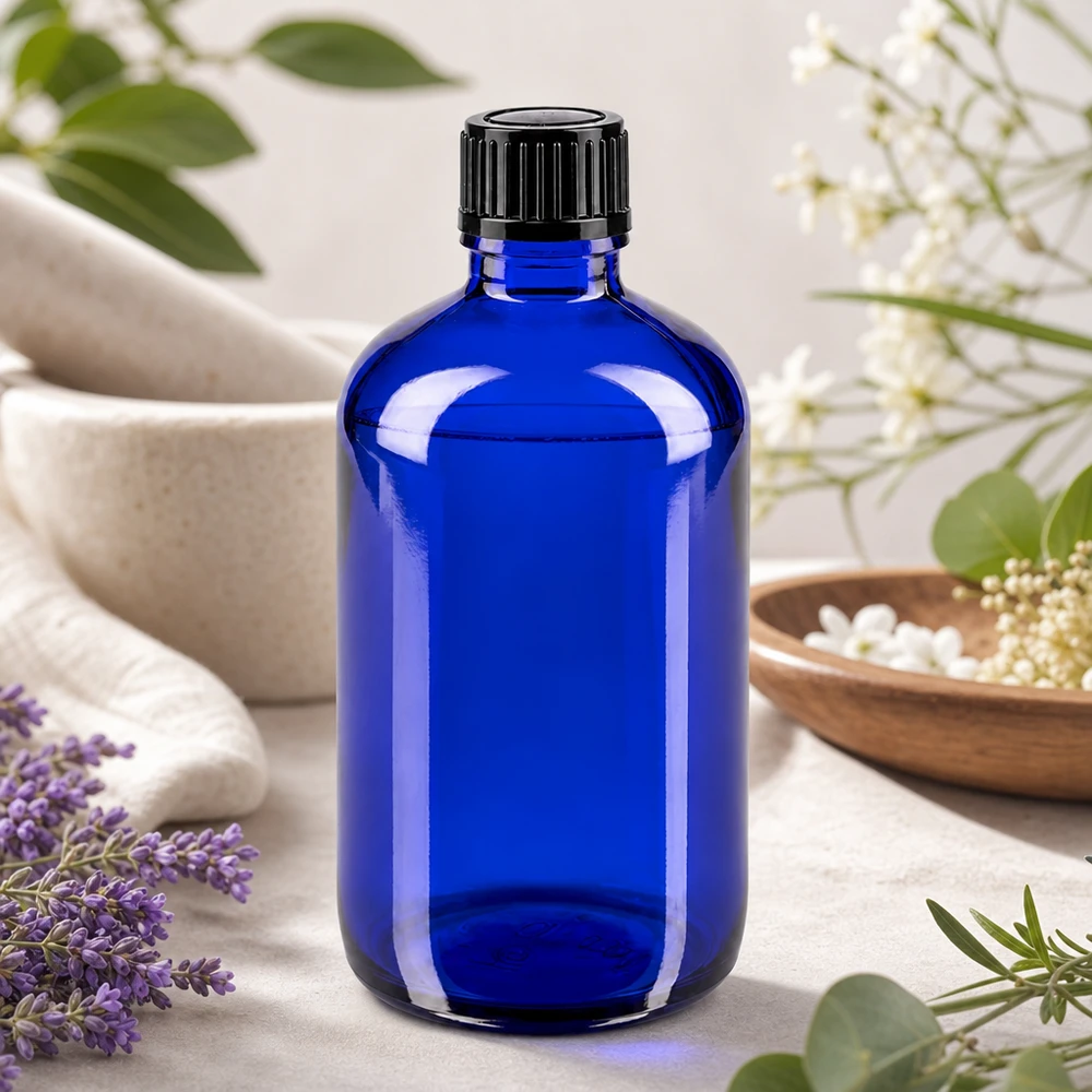 Flacon de pharmacie bleu 100ml bouchon vissable noir Std Flacon de pharmacie bleu cobalt de 100 ml avec un bouchon noir, à côté d'un mortier et d'herbes médicinales