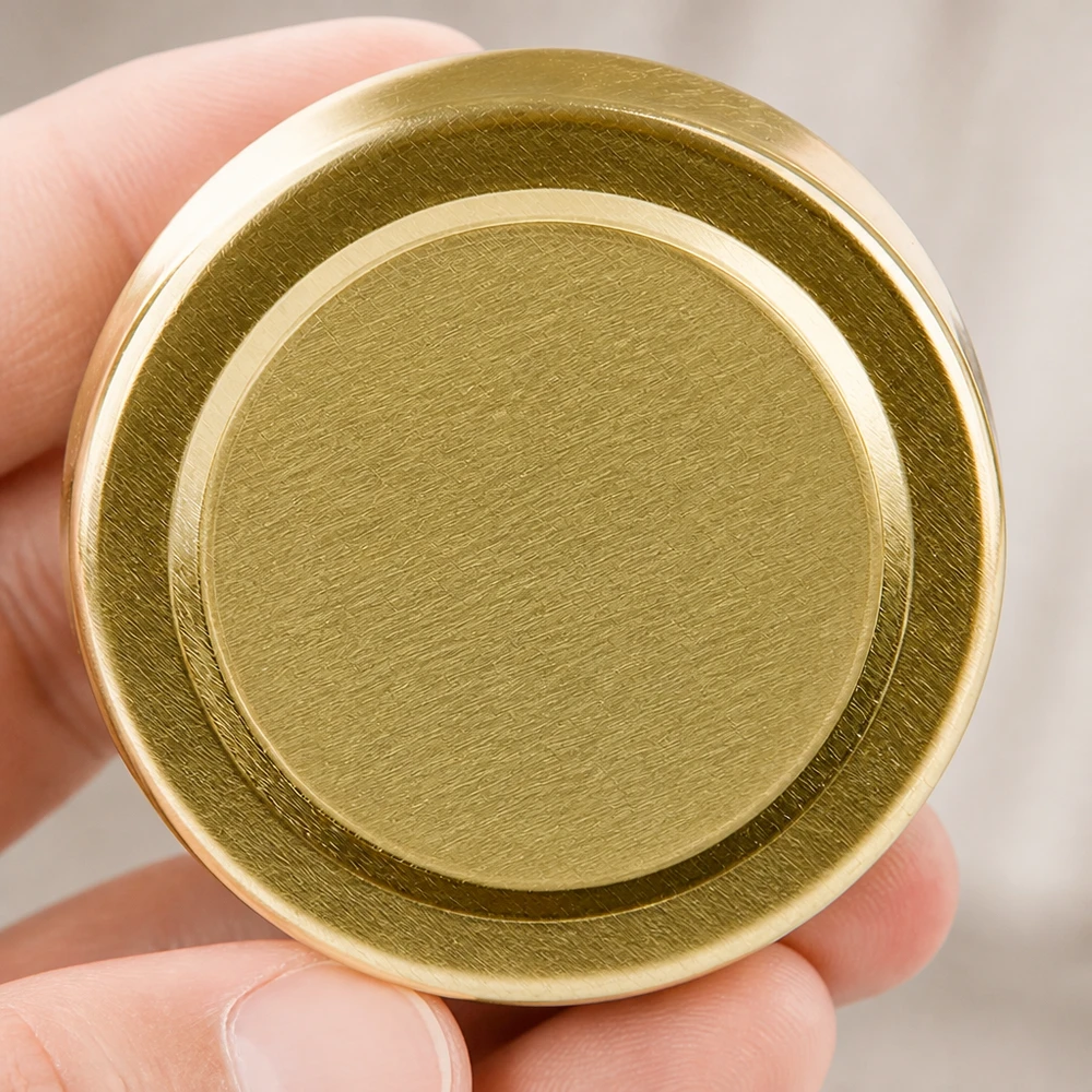 Couvercle à visser de 58 mm TO58deep gold UNiTWIST tenu entre les doigts, vue du dessous