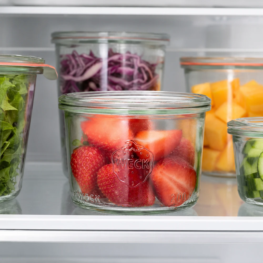 Bocal en verre de 200 ml WECK RR80 WECK Pot renversé 200ml RR80 avec des fraises fraîches dans le réfrigérateur à côté d'autres pots remplis de légumes et de fruits