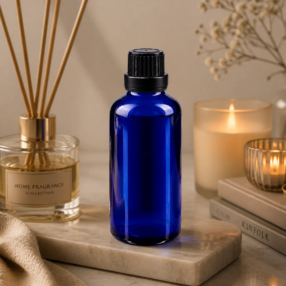 Flacon de pharmacie bleu 50ml bouchon vissable noir bouchon inviolabilité Flacon compte-gouttes bleu cobalt de 50 ml avec bouchon à vis, posé sur du marbre à côté d'un diffuseur de parfum d'ambiance