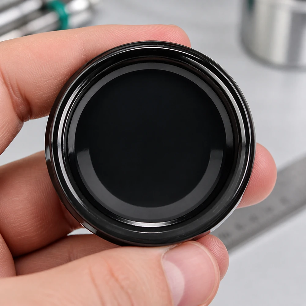 Main tenant un couvercle de bocal noir UNiTWIST TO63 BioSeal unitemp avec rebord apparent