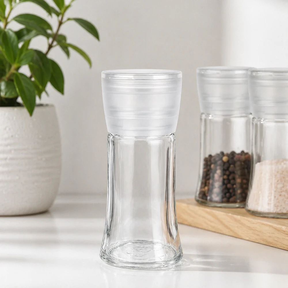 Pot à sel/épices 95 ml avec moulin Vario blanc Pot à épices vide de 95 ml avec moulin blanc Vario, à côté de grains de poivre et de sel sur une planche en bois